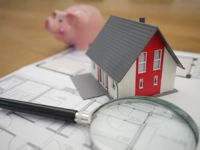 Model house on blueprints with piggy bank.